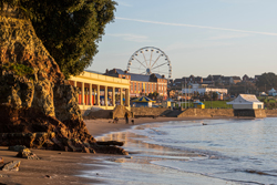 sunny beach scene with a ferris wheel and seaside promenade in the background during sunset